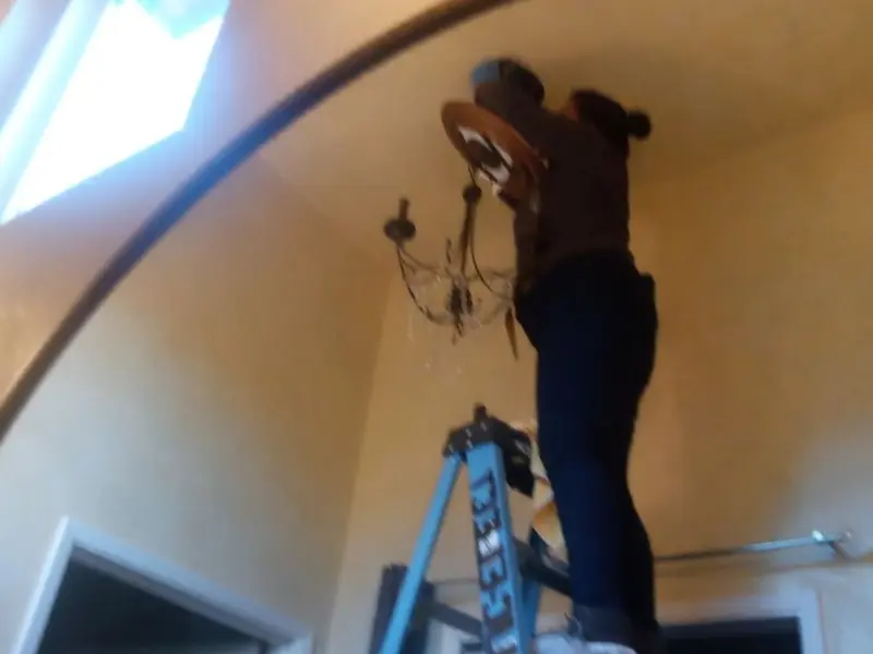 Electrician installing a chandelier in a Southern Shops residence